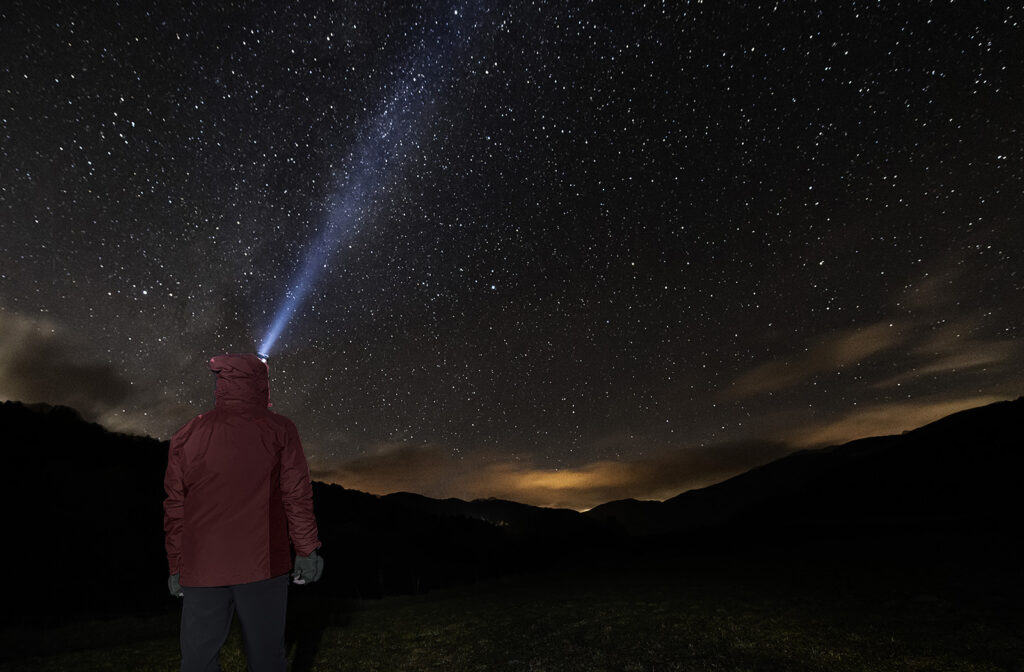 significant life journey concept man with headlamp looking at the starry night sky